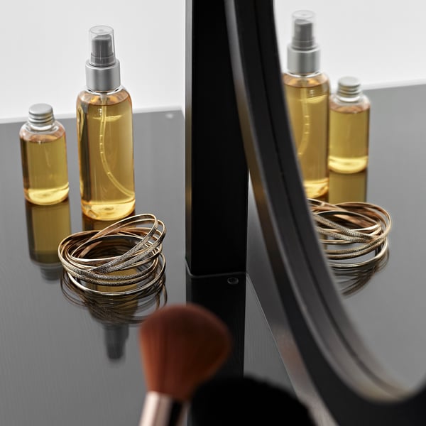 A sleek, modern makeup organiser with glass and pine drawer, showcasing golden spray bottles and bracelets.