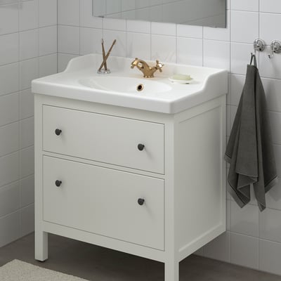 HEMNES bathroom vanity with golden tap, two drawers, sink, soap, and towel.