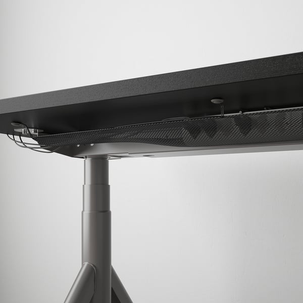 Close-up of IDÅSEN desks height-adjustable leg and cable management net.