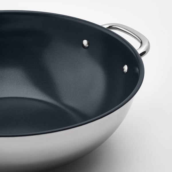 Stainless steel wok with dark non-stick surface and sturdy handles, cleaned and ready for cooking.