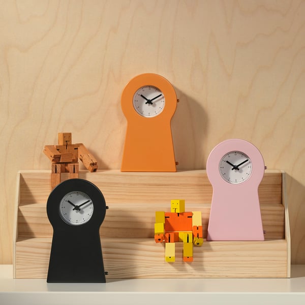 Colourful clocks: black, orange, pink on shelves, with robot decor.