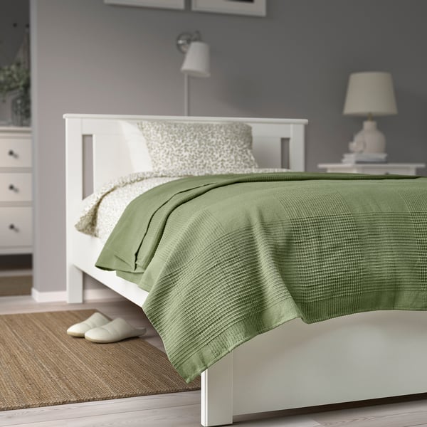 Cosy bedroom with INDIRA green cotton bedspread on double bed, beige slippers, white bed frame, matched by lamps.