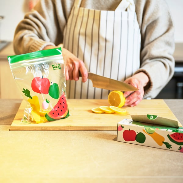 Person slicing lemon on cutting board with colourful IKEA bags.