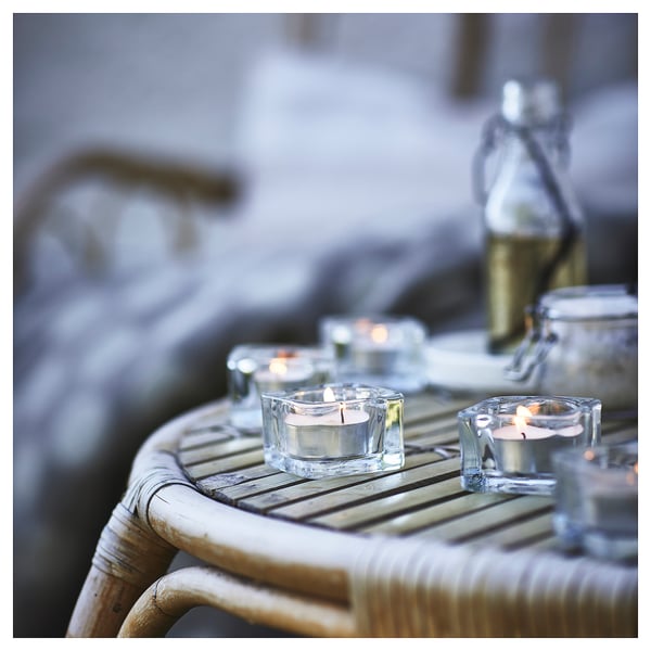 Small lit candles in clear glass holders on a bamboo table.