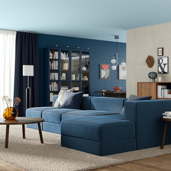 Blue sofa, dark wall, wooden table, lamp, rug, bookshelf - modern living room.