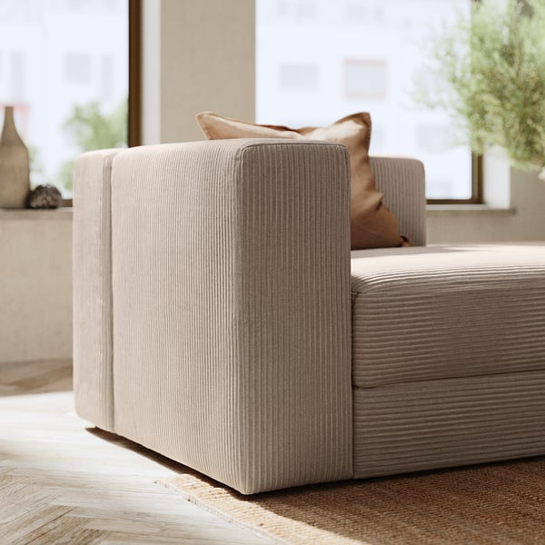 Modern beige sofa with ribbed fabric and brown pillows, stylish and cosy.