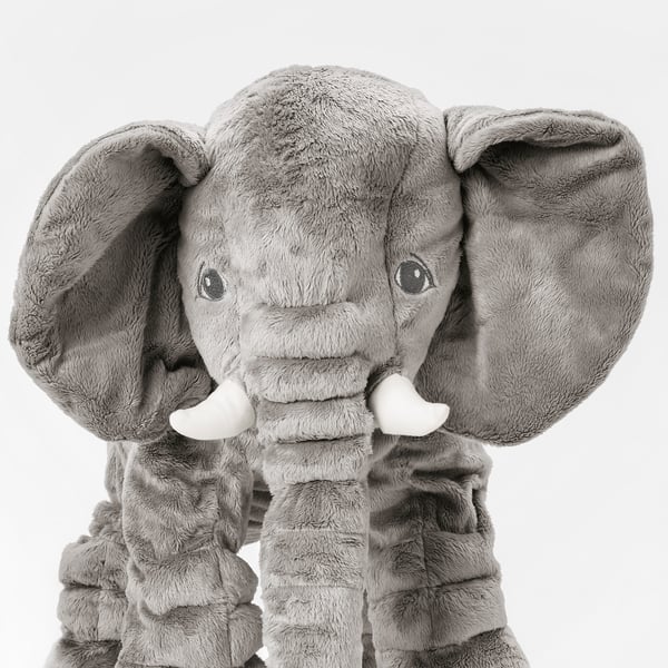 Stuffed elephant toy with soft, plush grey fur, large floppy ears, and white tusks. Its a cuddly, comforting companion.