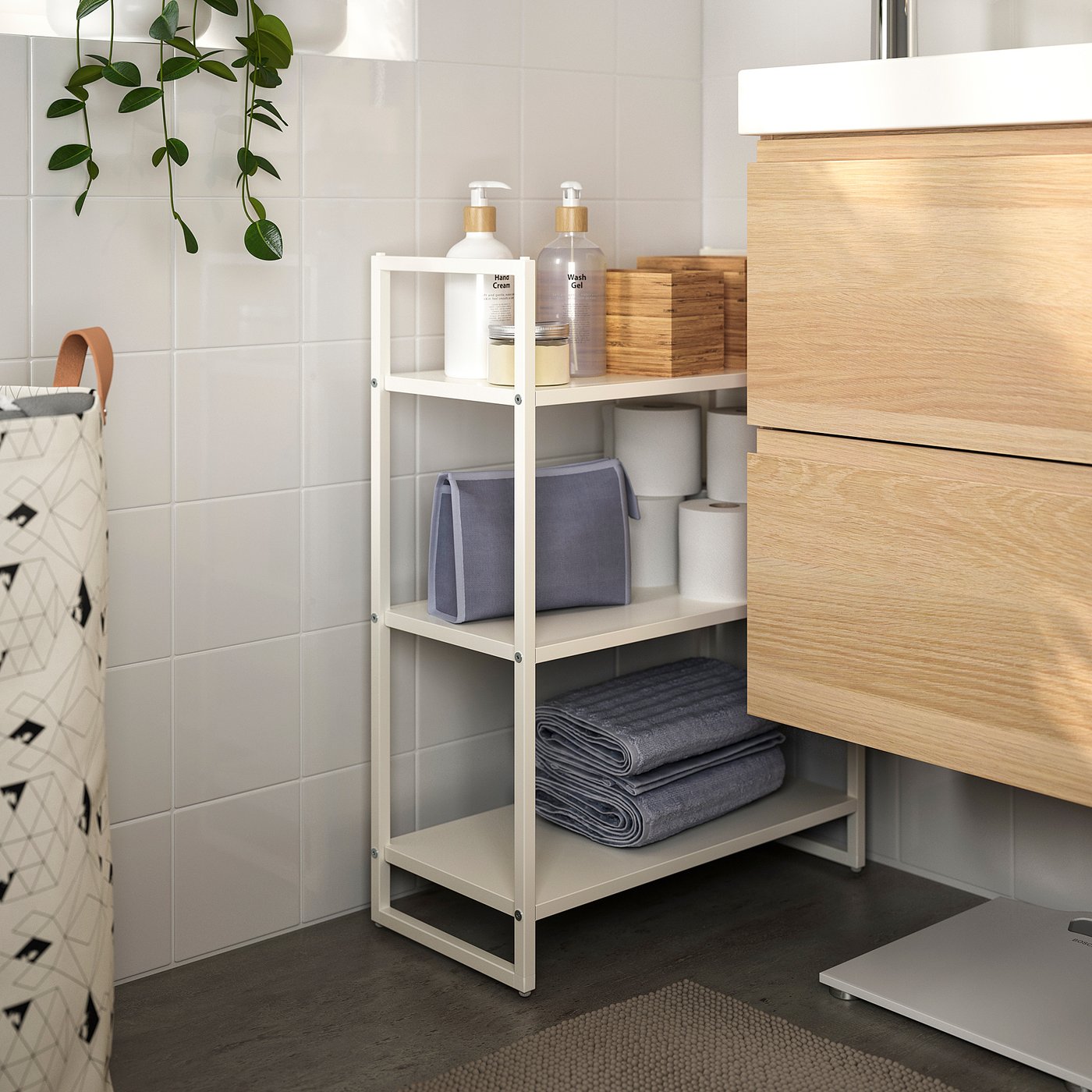 White metal storage shelf with towels and toiletries between vanity and wall.