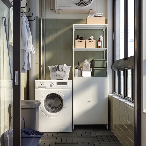 White JOSTEIN storage unit in laundry room with washing machine, baskets, and bottles. Rust-resistant steel.