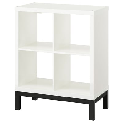 A white KALLAX shelving unit with a black underframe. It has an open, airy design with multiple compartments.