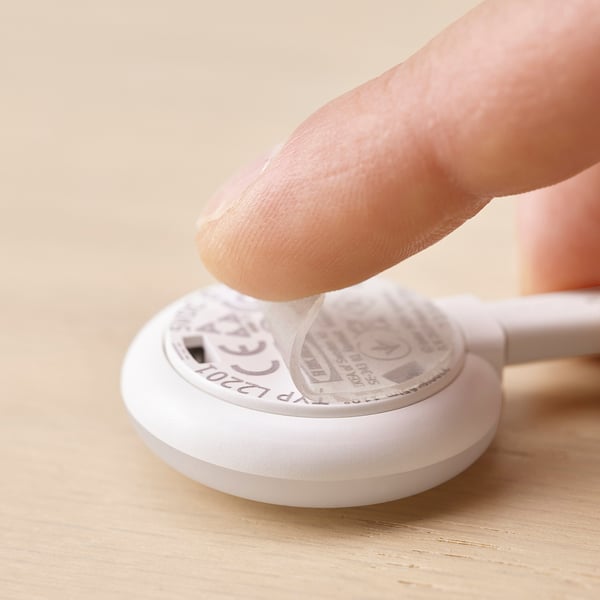 A hand presses a button on a white KAPPLAKE spotlight, featuring easy-to-use gel-pad mounting.