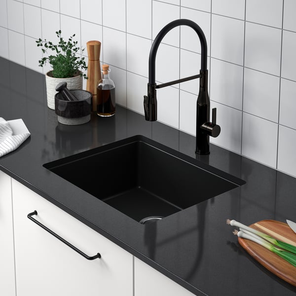 Modern kitchen sink with black tap and countertop. Include a cutting board and vegetables, showing practicality and space efficiency.