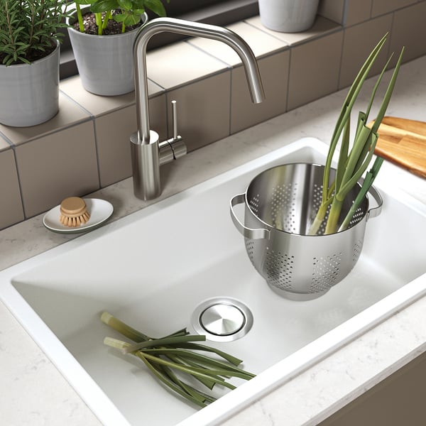 Kitchen sink with green onions and scrubber.