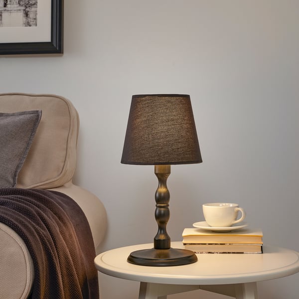 KINNAHULT lamp on table beside chair with blanket.