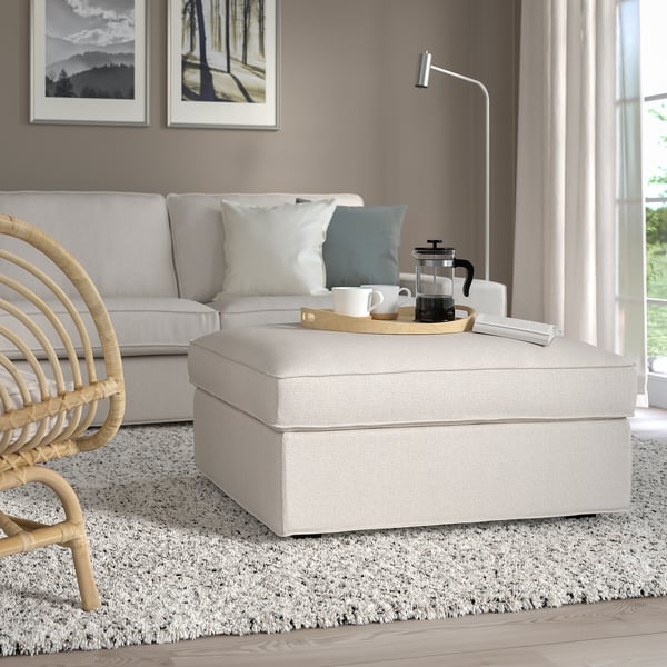 Modern living room with KIVIK footstool, sofa, wicker chair, lamp & nature art.