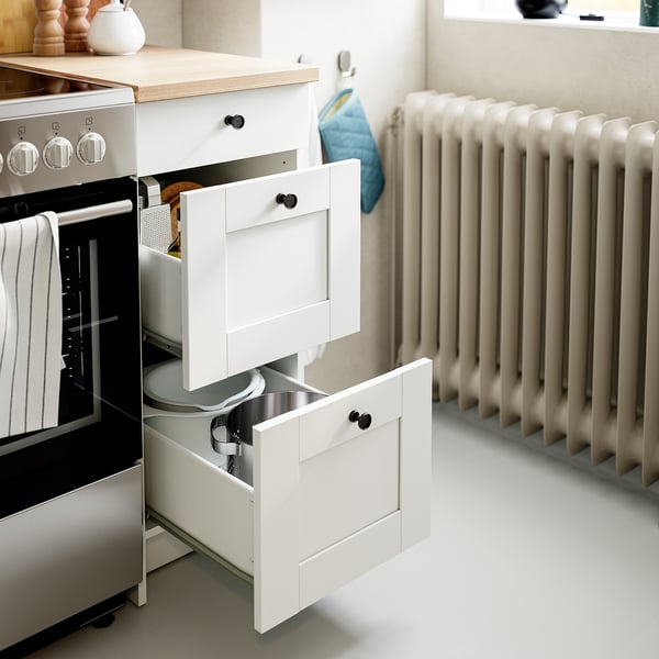 Kitchen cabinet with open drawers, storing utensils. White framed drawers, part of KNOXHULT series.