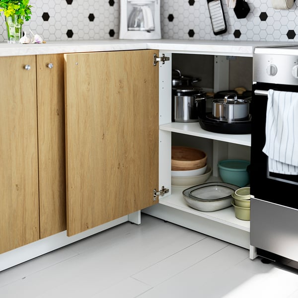 Kitchen cabinet open showing organised pots, pans, and bowls on shelves next to oven.