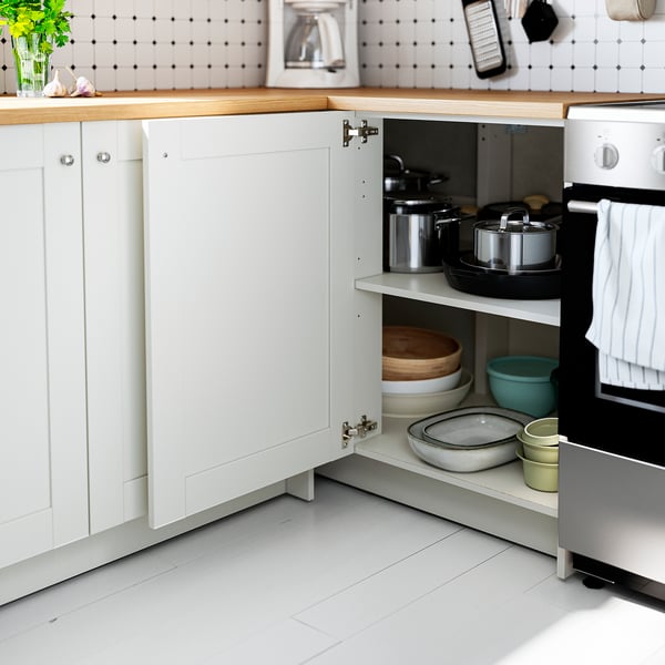 Open kitchen cabinet revealing pots, pans, and bowls neatly organised on adjustable shelves.