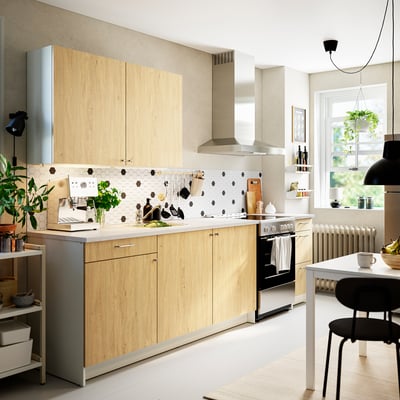 Modern kitchen with KNOXHULT wood cabinets, marble counter, black dot backsplash, stainless appliances, efficient storage.