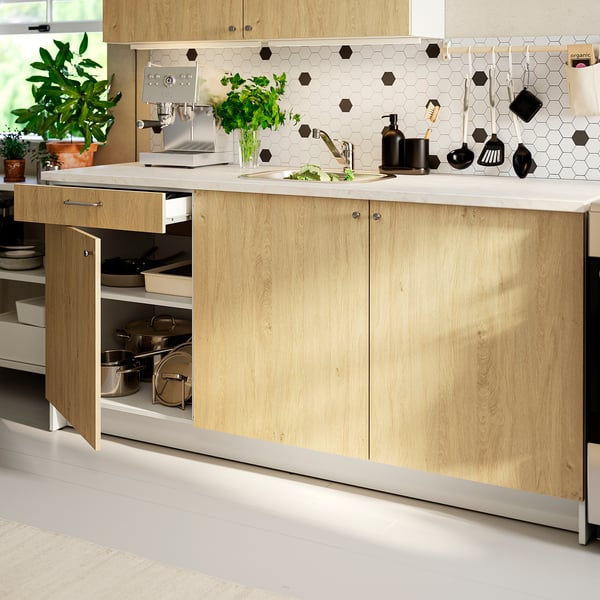 Modern kitchen with wood cabinets, marble counter, and tile backsplash. Open drawers and workspace.