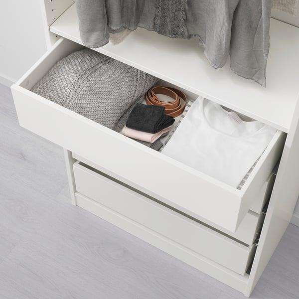 White wardrobe drawer, open showcasing folded clothes and accessories neatly organised in compartments.
