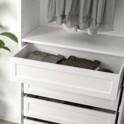 Drawer partially open showing folded clothes in white wardrobe.