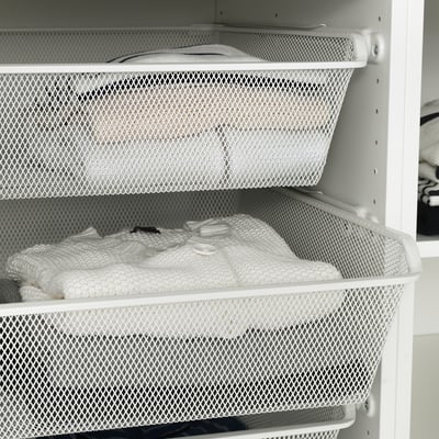 White mesh storage baskets in a cabinet, holding folded clothes, allowing air circulation and easy viewing.