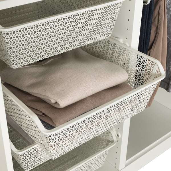 White mesh KOMPLEMENT basket holds folded clothes in wardrobe, promoting air circulation.