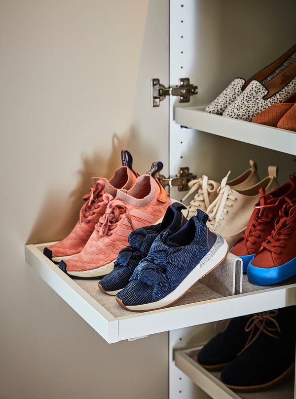 White closet shelf with pink, blue, and beige trainers neatly organised.