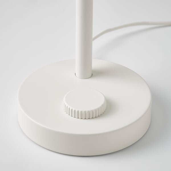 Modern white lamp with round base, textured switch, clean lines.