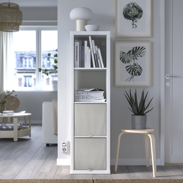 Stylish living room with white KOSINGEN storage box, grey plant, art prints, light wood stool.