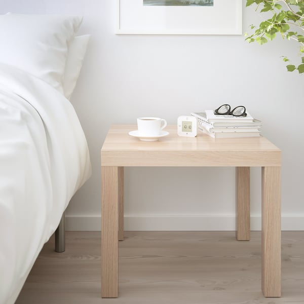 LACK side table as bedside table beside bed, holding cup, books, glasses, complementing white bedding in minimalist bedroom.