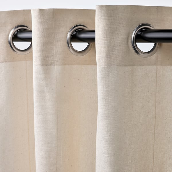 Off-white curtains with large eyelets hanging on a rod. The eyelets allow the curtains to glide smoothly for easy opening and closing.