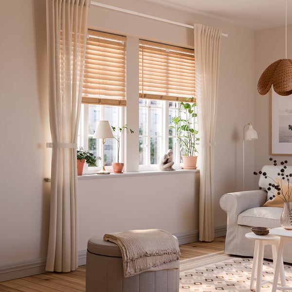 Beige LENDA curtains, wooden blinds, cosy chair, potted plants.