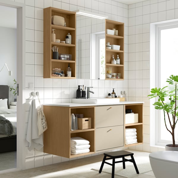 Modern bathroom with wall-mounted LETTAN light oak cabinet, mirrored doors, wood vanity, and black stool.