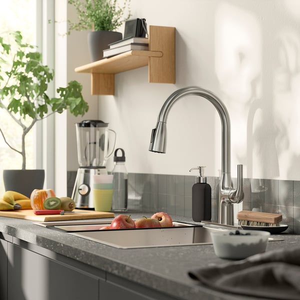 Modern kitchen sink with silver MACKSJÖN tap, dark countertop, and stylish decorations.