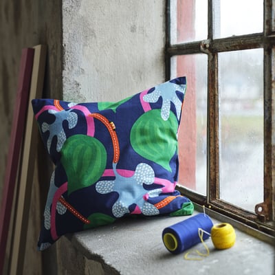 MÄVINN cushion with fruit design on windowsill, next to yarn.