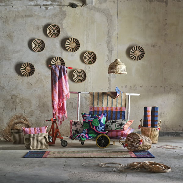 Room with woven textiles: colourful pillows, baskets, and blankets on a jute runner.