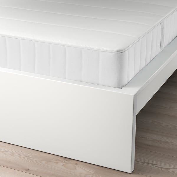 A white MALM bed with clean design, adjustable bed sides, and high headboard for sitting comfortably.