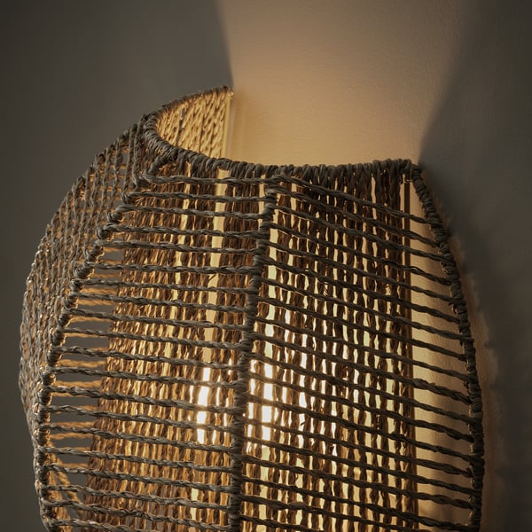 Handwoven wall lamp emits warm light, enhancing ambiance with natural sedge material.