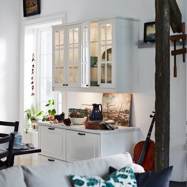 Kitchen with white cabinets, plants, lights, and guitar.