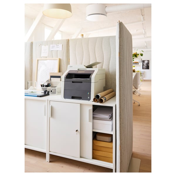 Modern office space with grey acoustic screen, printer, desk, and decor.