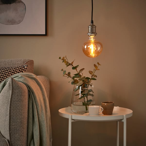 Cosy nook: warm MOLNART bulb & eucalyptus. Grey blanket, abstract art.