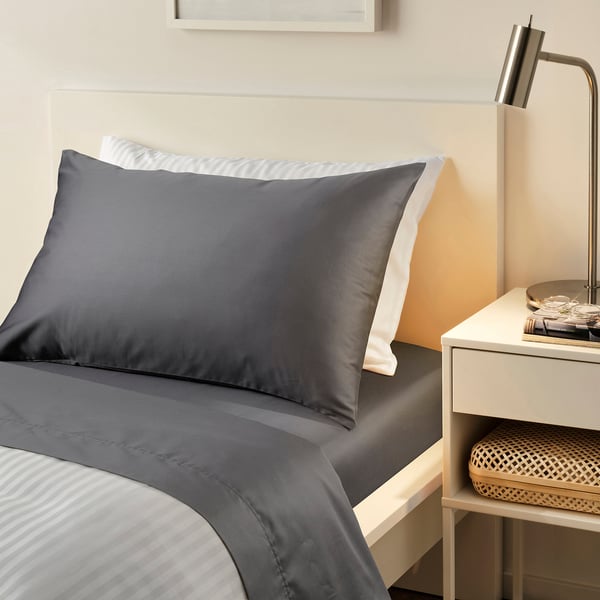 Modern bedroom with NATTJASMIN graphite bedding. Luxe silk-like finish, sateen-weave. Tidy bedside table nearby.