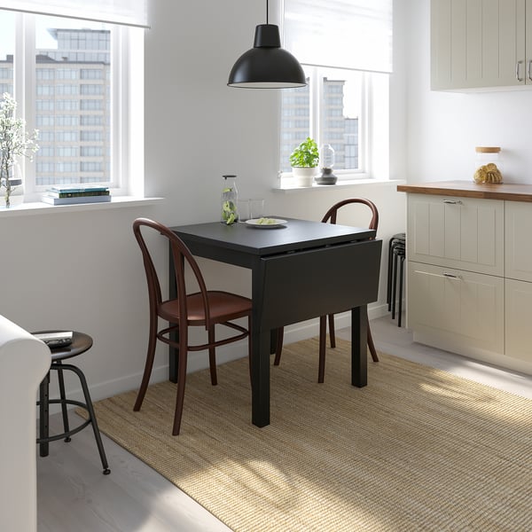 Small apartment dining corner with NORDVIKEN black drop-leaf table & wooden chairs. Modern, space-saving design.