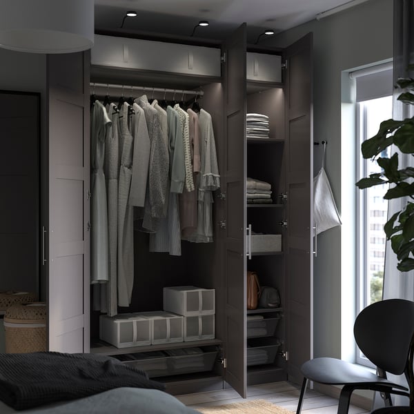 Open wardrobe with clothes and storage boxes. Modern design, dark brown, multiple shelves and drawers.