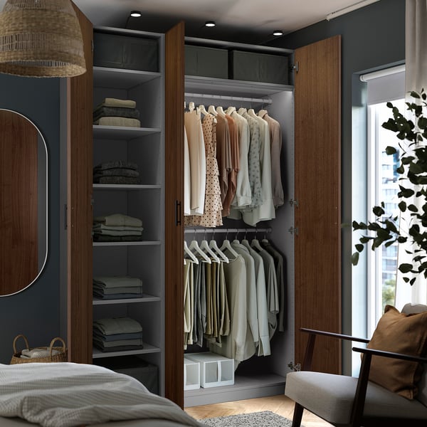 Open wardrobe with clothes on hangers and folded clothes on shelves. Lighting inside.