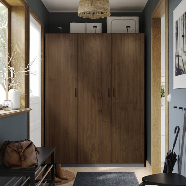 Modern entryway with large PAX wardrobe, woven lampshade, black bench, and decor on narrow table.