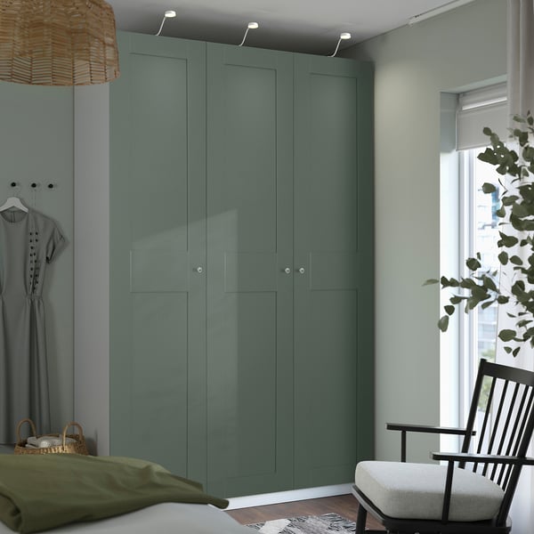 Modern bedroom with teal PAX wardrobe, armchair, plant.