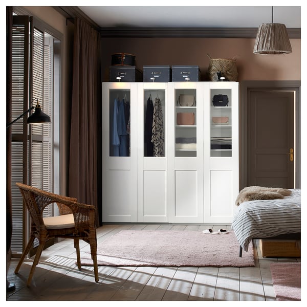 Modern bedroom with PAX wardrobe, clear glass doors, and organised clothes.